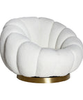 Sillón giratorio estilo art deco tapizado en bouclé blanco con base dorada.